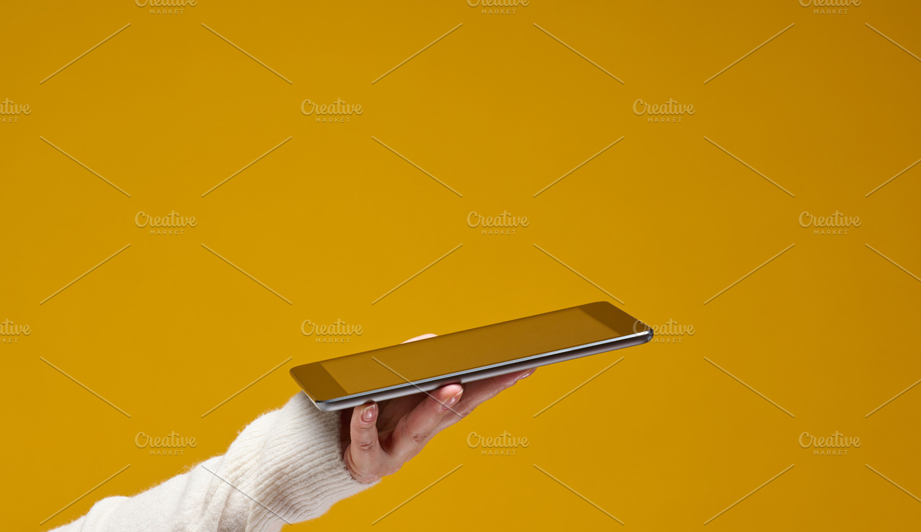 Hand wearing a white sweater holds a silver tablet against a sol, a Technology Photo by ndanko