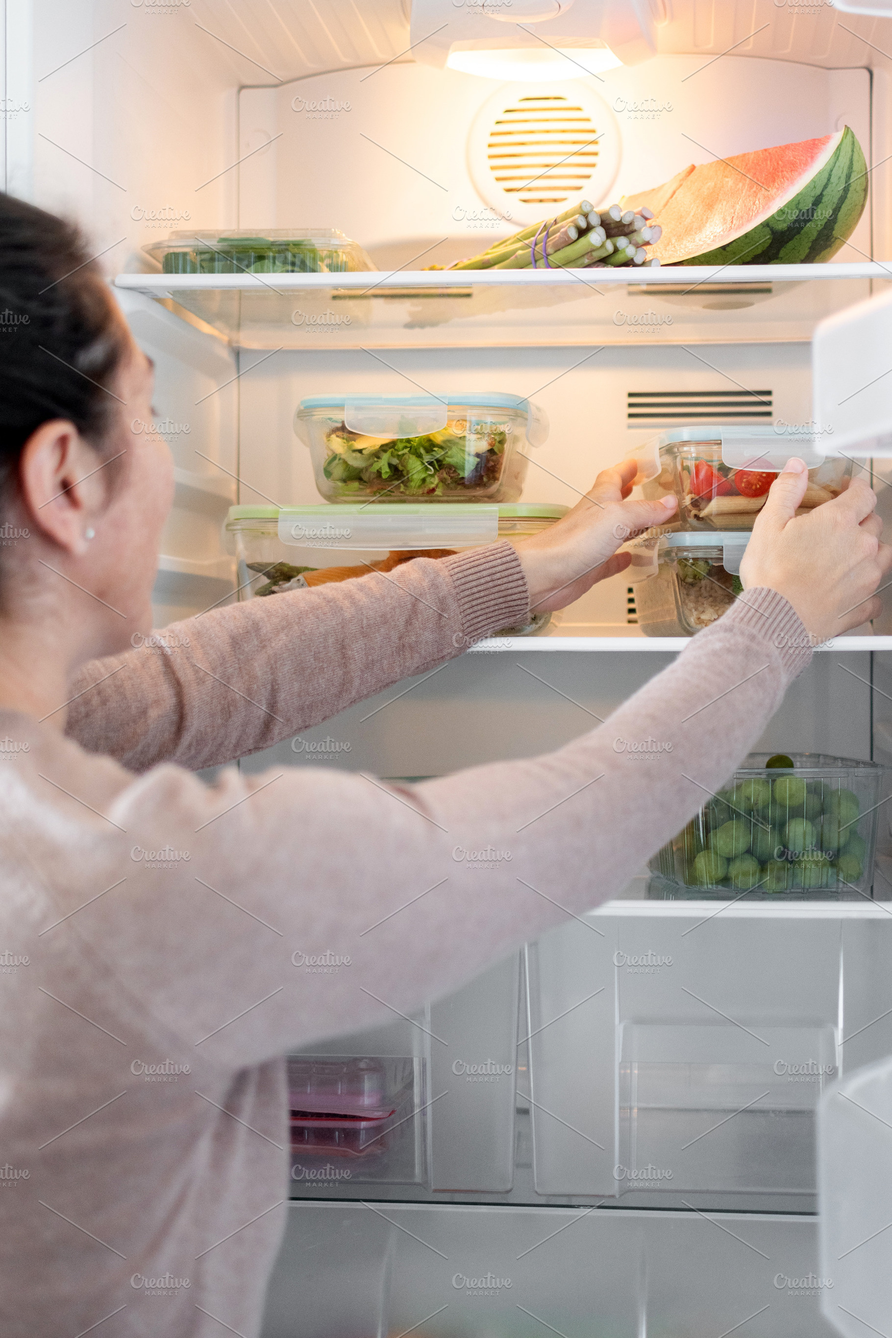 Woman Organizing Healthy Meal Prep Containers in Refrigerator at Home, a Food & Drink Photo by etorres69
