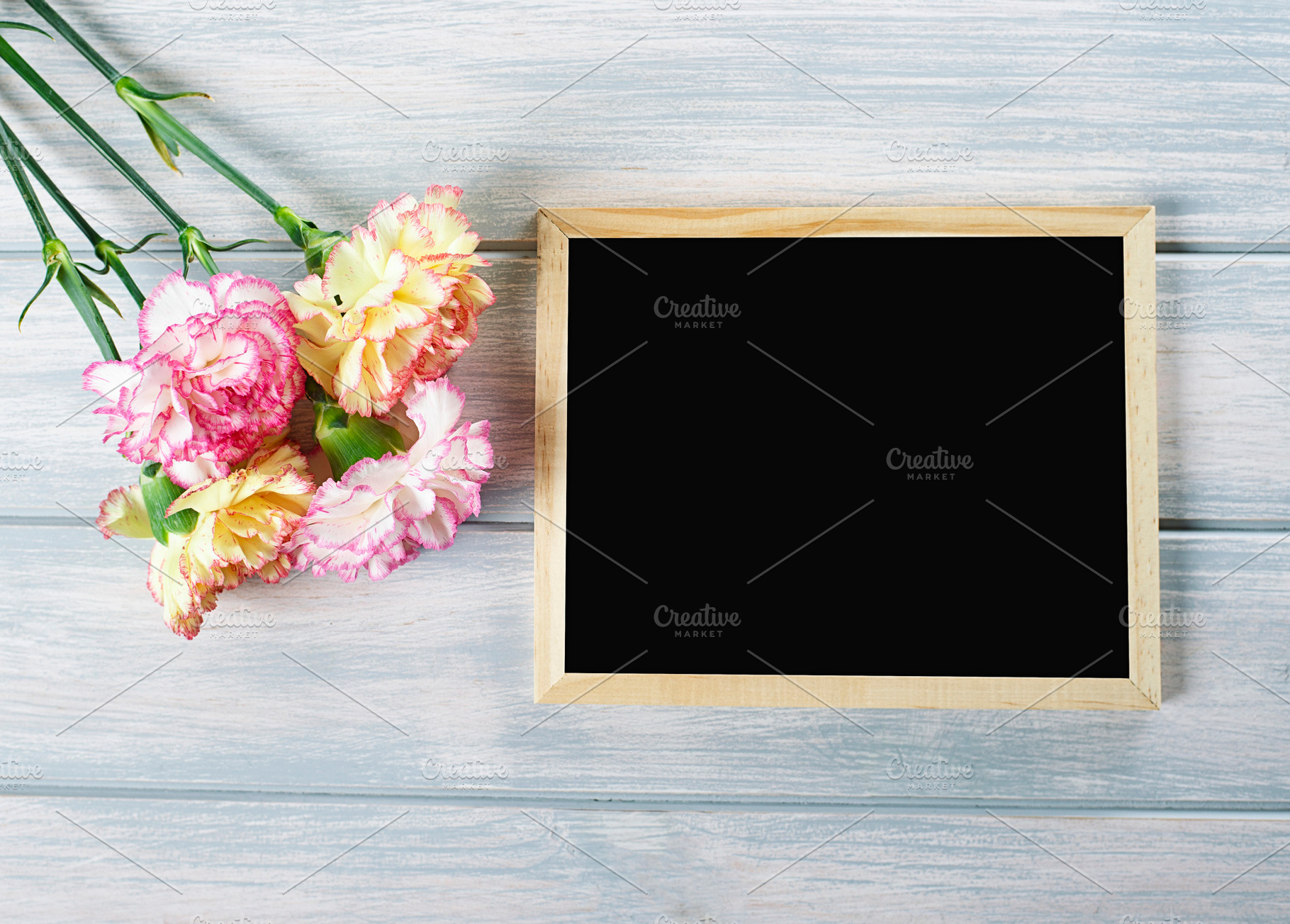 Close up of pink and yellow flowers next to blackboard on wooden table. Copyspace Mockup., a Nature Photo by José Luis Agudo
