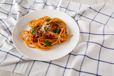 Homemade Bucatini all Amatriciana Pasta in a white plate on clot, a Food & Drink Photo by LiudmylaChuhunova