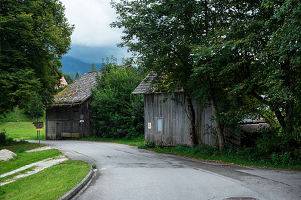 the road leads to the village with houses. alpine forest and mountains
