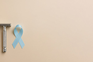 Men health awareness with blue ribbon and razor on beige backgro, a Photo by Dvoevnore photos