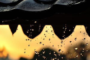 Raindrops fall from a roof during su, a Photo by Tanuart
