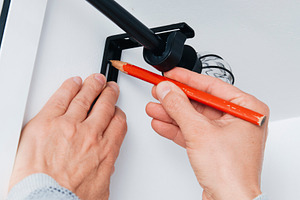 a man marking a point on the wall with a pencil, a Photo by Nito