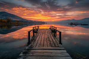 Wooden dock lake sunrise fiery sky m, a Photo by Pixeness Studio