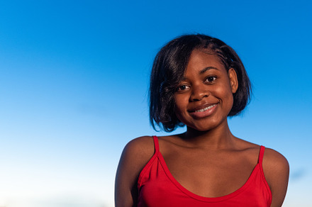portrait of a young african woman smiling to the camera, a Person Photo by Iván Moreno STOCK PHOTO