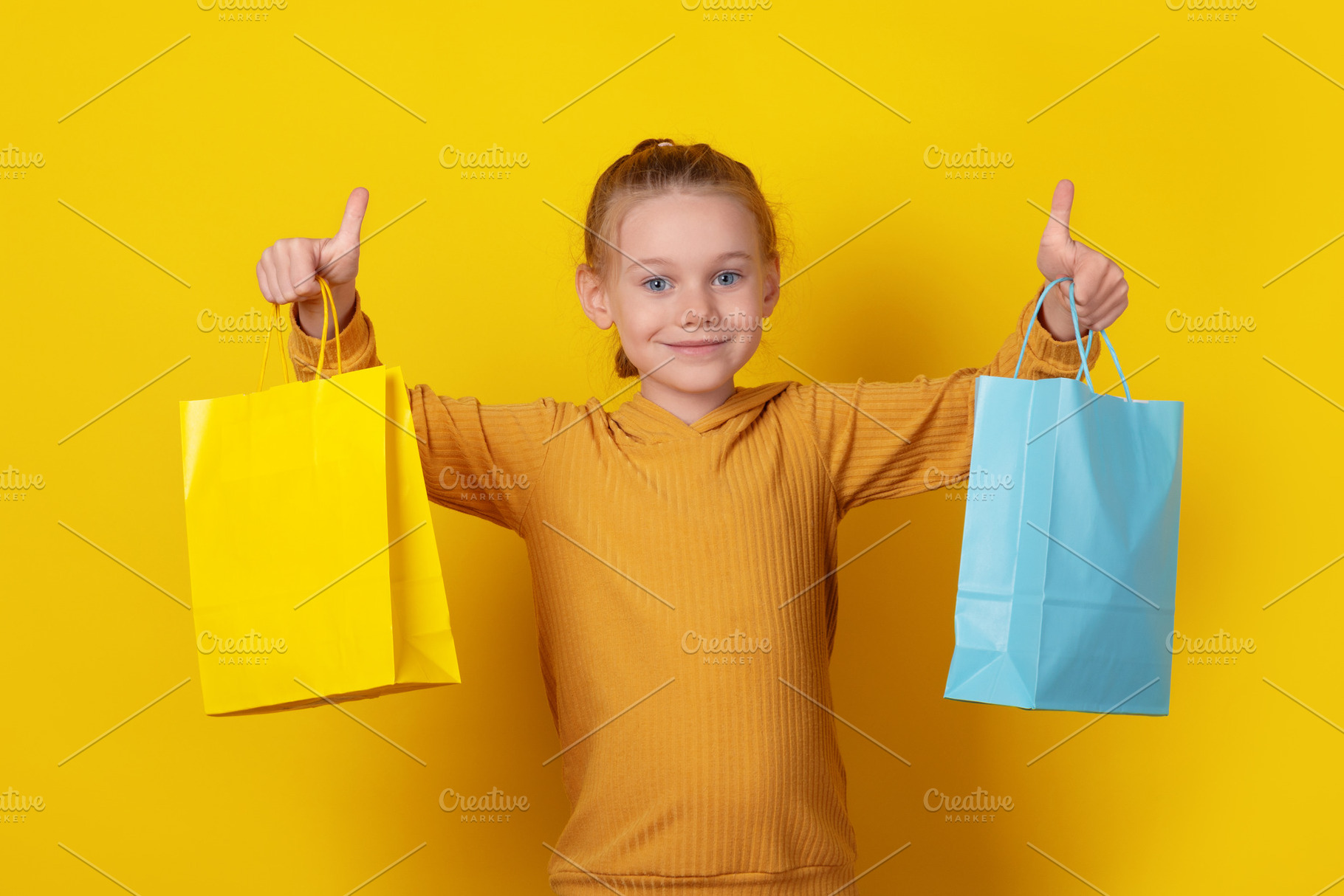 Smiling young girl in hoodie holding colorful shopping bags and, a Person Photo by Ales Munt