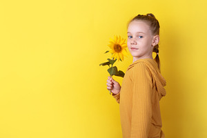 Smiling young girl holding a sunflower, standing against a vibra, a Person Photo by Ales Munt