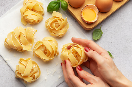 Chef preparing homemade tagliatelle pasta with eggs and basil, a Food & Drink Photo by Olena Rudo