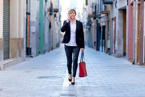 Businesswoman walking and talking on smartphone, a Photo by RF Images