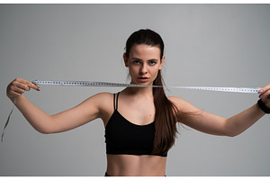 Young woman holding a measuring tape, a Sports & Recreation Photo by volodymyrshtun13795