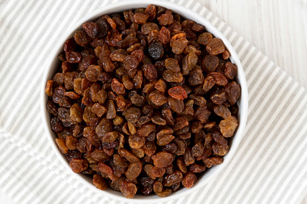 Dried Brown Raisins in a Gray Bowl, top view. Flat lay, overhead, a Food & Drink Photo by LiudmylaChuhunova