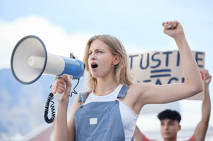 Justice, megaphone and woman protest for justice, community solidarity and human rights voice on racism, government and women equality. Crime, crowd and people with cardboard sign and freedom speech, a Photo by Peopleimages.com