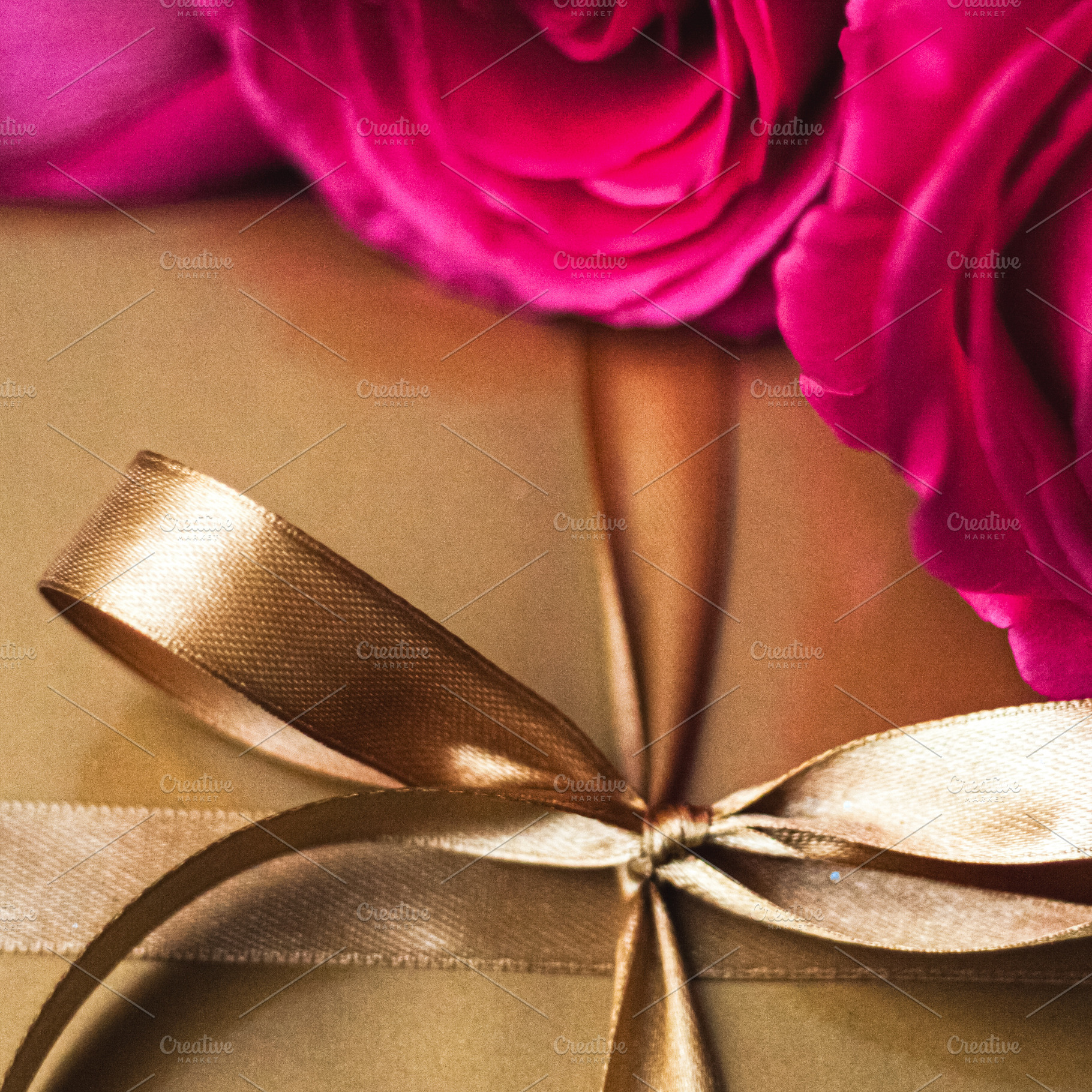 Gift box wrapped in golden paper with a satin ribbon bow and vib, a Photo by Studio ANNA