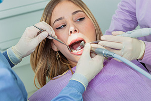 Dentist performing dental cleaning on young woman's teeth, a Health & Medical Photo by Antonio Gravante Market