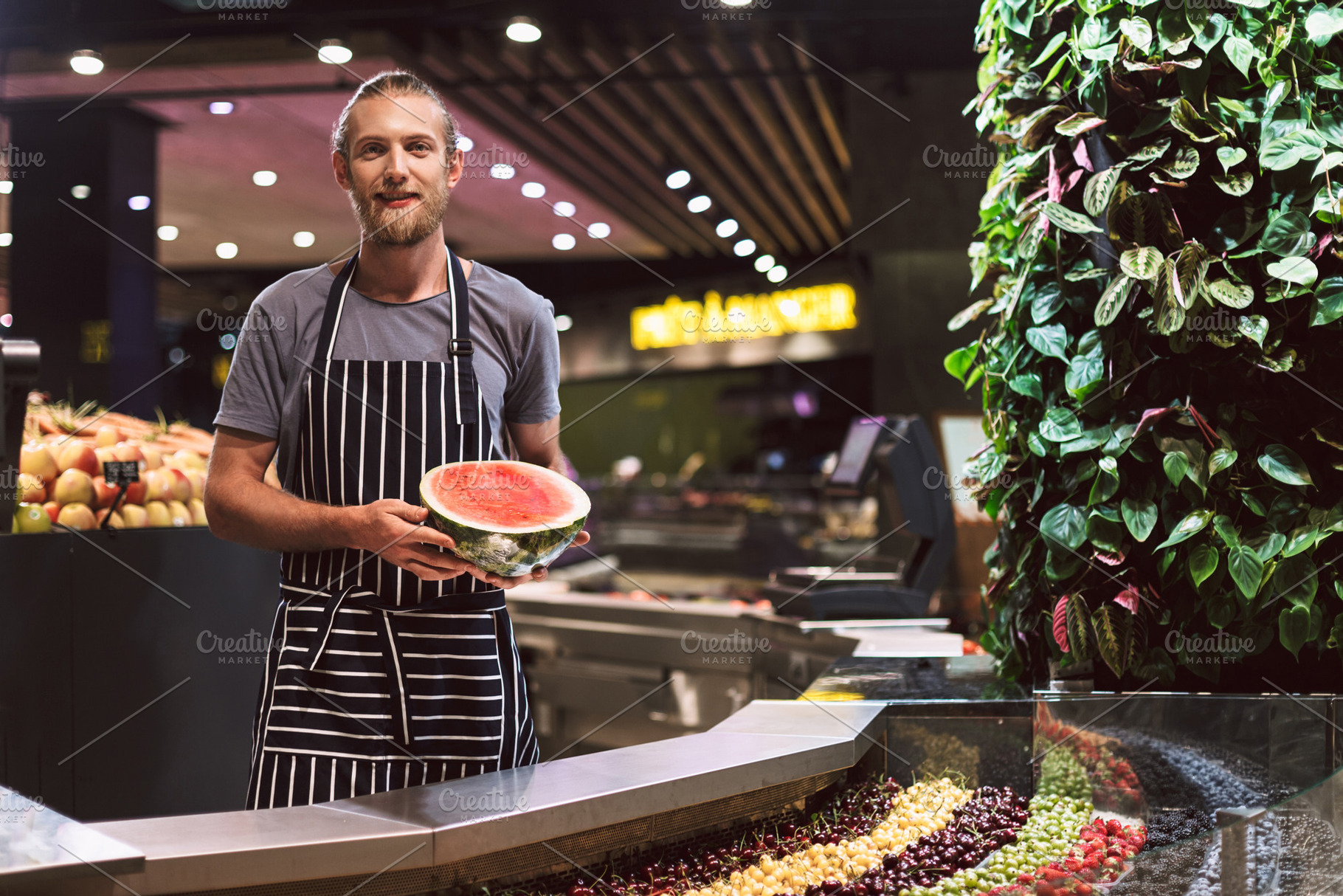 Young salesman in striped apron behi stock photo containing berries and person, a Food & Drink Photo by Garetsworkshop