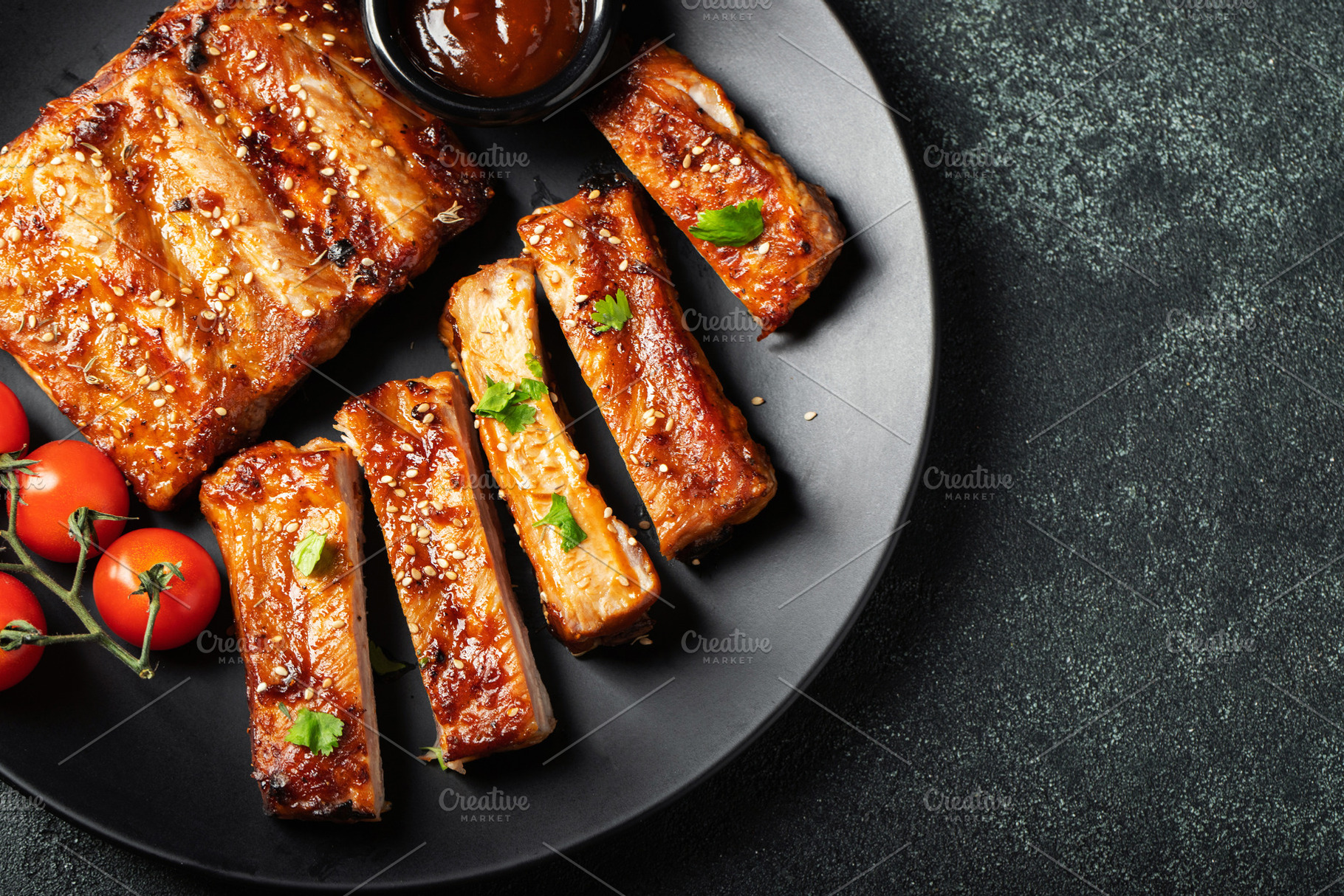 Hot grilled spare ribs from a summer BBQ served on a plate with sauce. Top view, a Food & Drink Photo by Budarinphoto