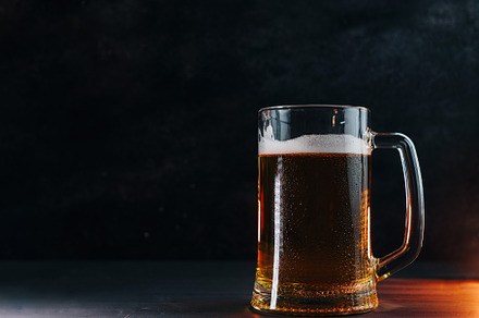 Light cold beer mug with water drops on a black table , backlight