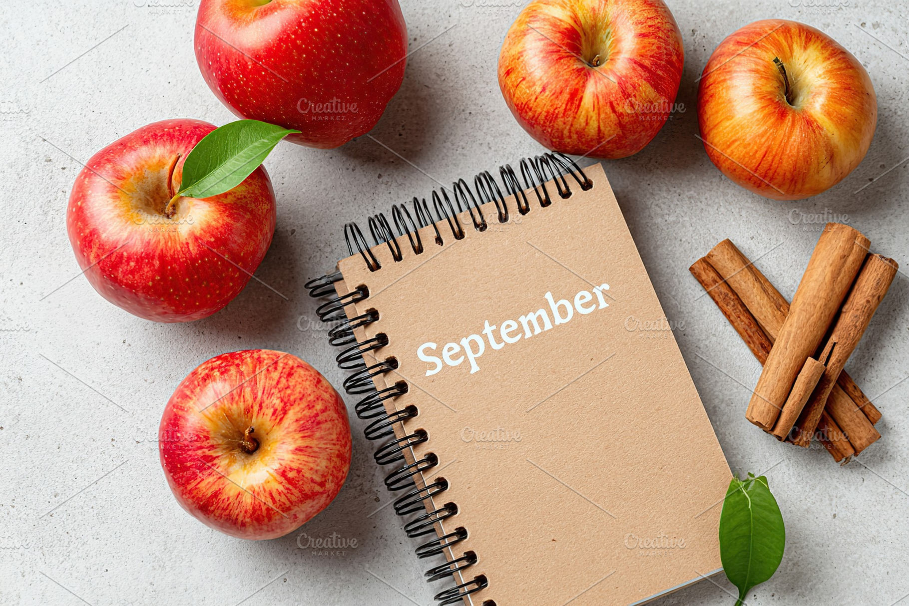 Fresh red apples with a notebook celebrating September and cinnamon on a gray s, an Abstract Photo by AlyaAnd