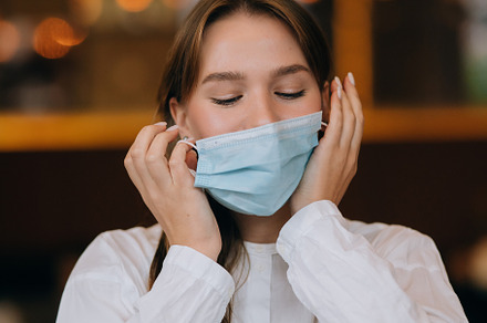 Girl in takes off her protective medical face mask