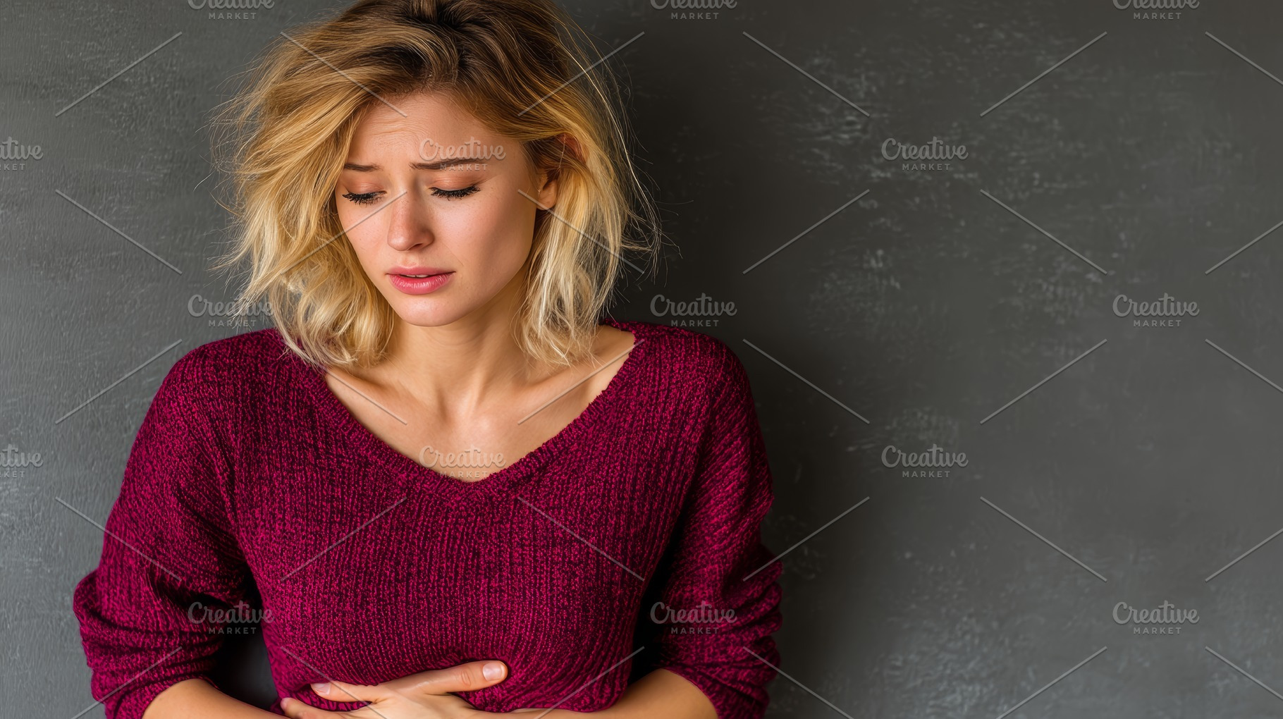 Woman experiencing discomfort holding stomach against a dark background, a Photo by AS photostudio
