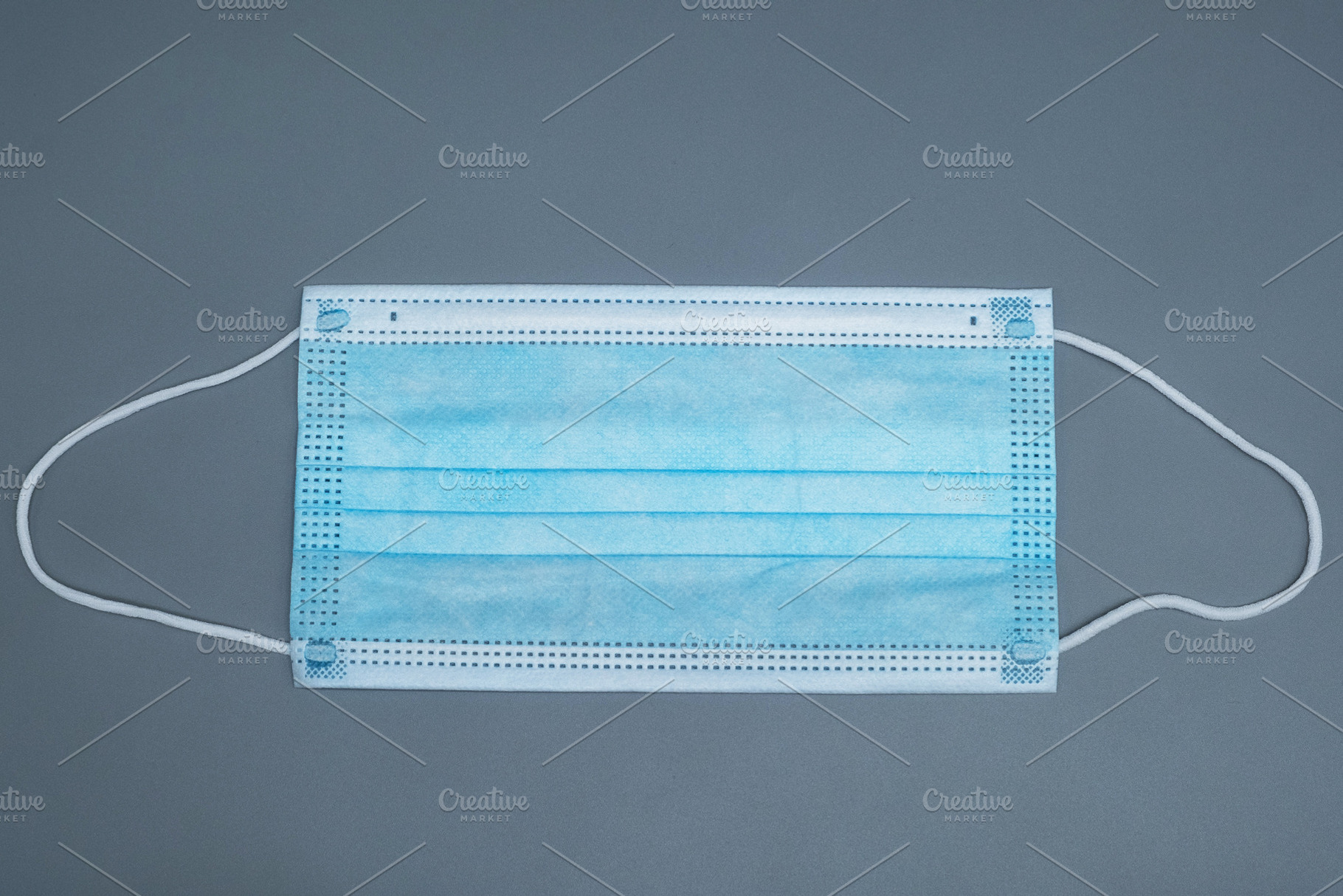 Disposable blue medical face mask on a grey background. Protective 3-ply surgic, a Health & Medical Photo by Rohan Photography