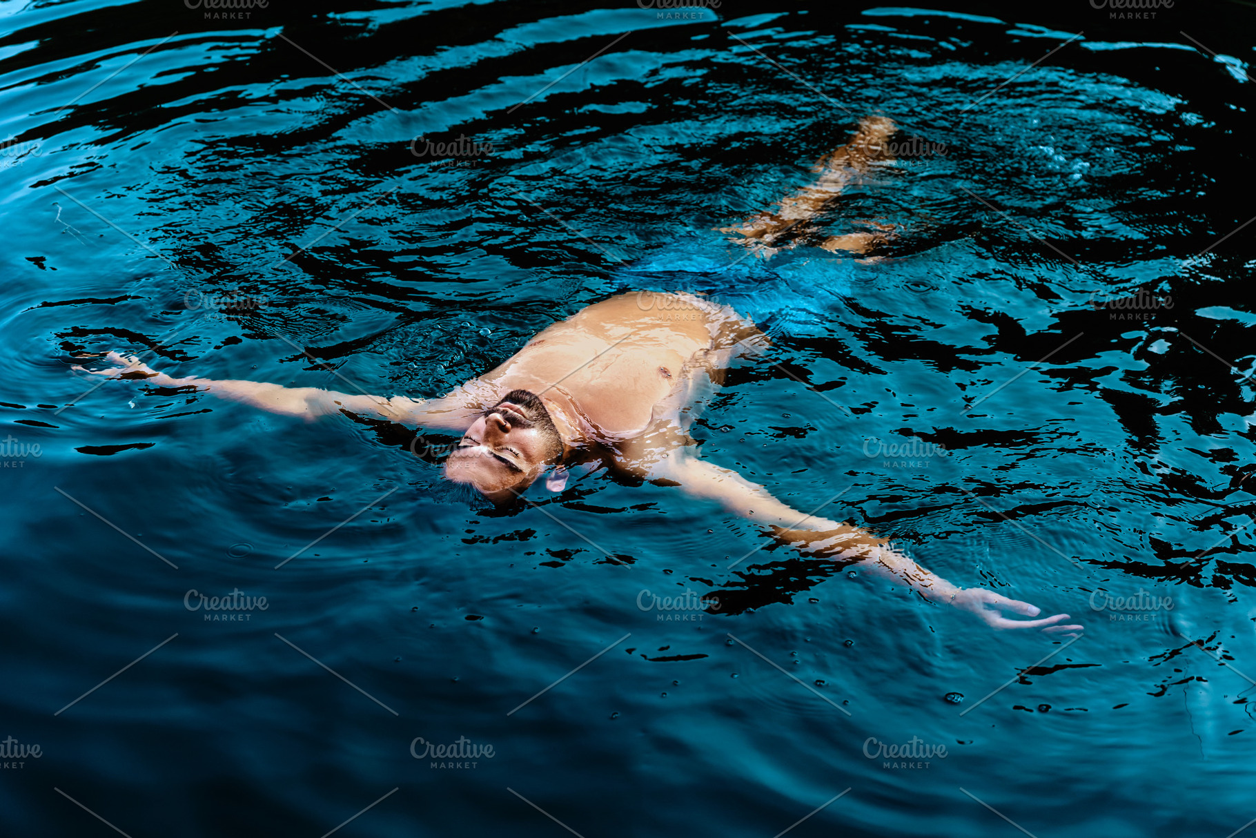 Man floating calmly in blue water, a Person Photo by Perpis