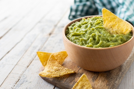 Mexican guacamole with nacho chip in wooden bowl on rustic woode, a Food & Drink Photo by etorres69