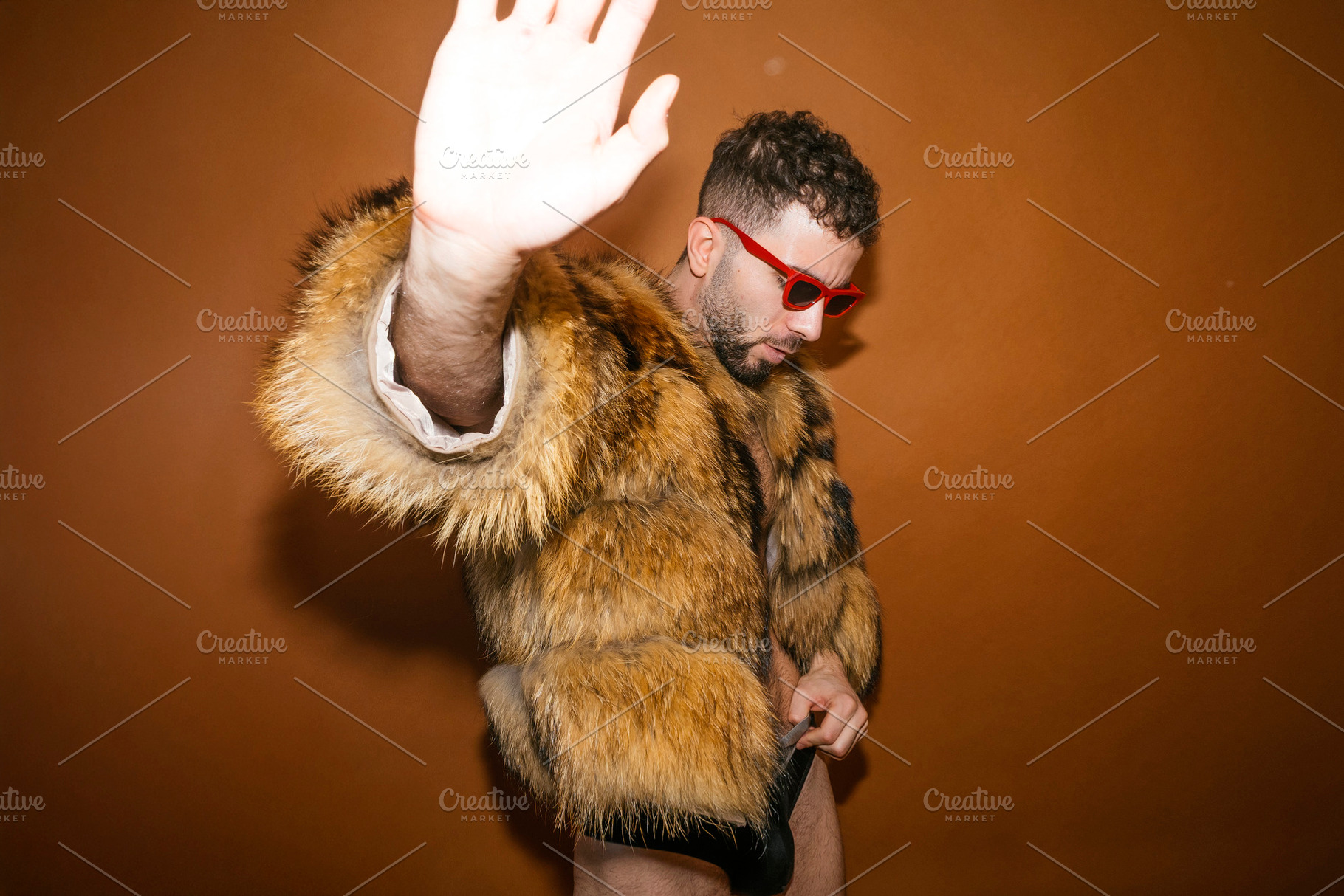Wearing fur coat and red sunglasses with hand gesturing stop, a Photo by karrastock