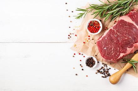Raw beef steak with rosemary and seasonings on white wooden background, a Photo by AlyaAnd