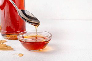 Tasty golden maple syrup in bottle, bowl and spoon, a Food & Drink Photo by Rimma