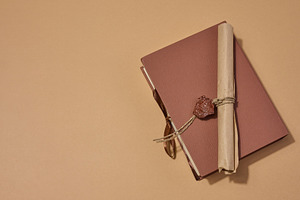 A closed book with a sealed scroll lying on top, on a neutral ba, an Abstract Photo by ndanko