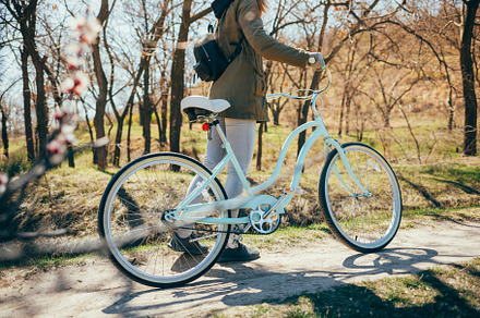 Young woman with her bike walking in park, a Person Photo by progressman