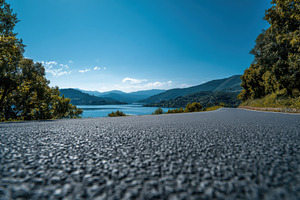 Asphalt road overlooking a tranquil, a Photo by Pixeness Studio