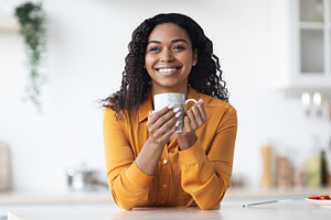 Closeup of happy pretty black woman enjoying morning coffee