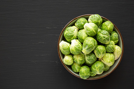 Raw Organic Brussel Sprouts in a Bowl on a black background, top, a Food & Drink Photo by LiudmylaChuhunova