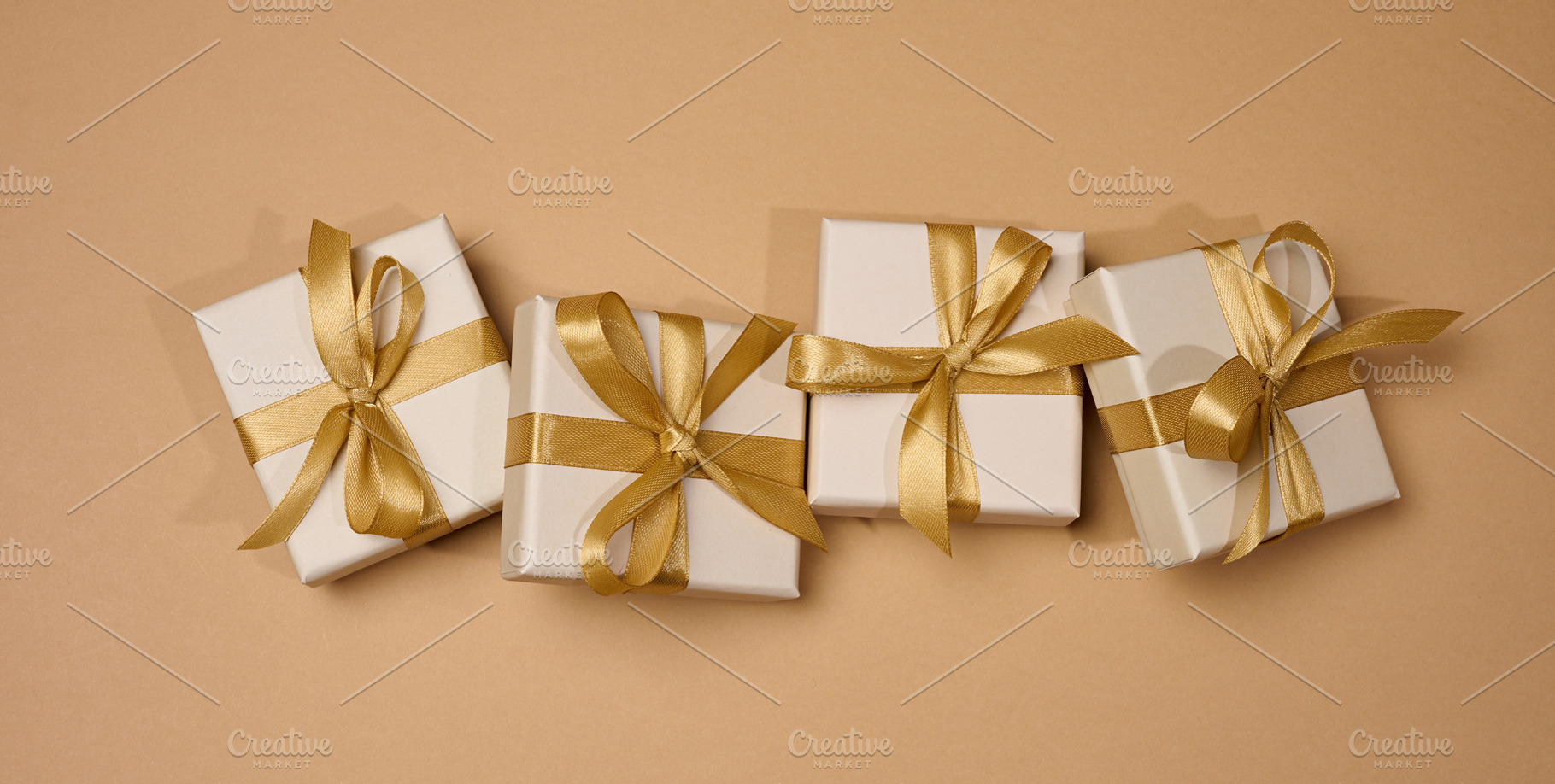 Boxes tied with golden ribbon on beige background, a Holiday Photo by ndanko