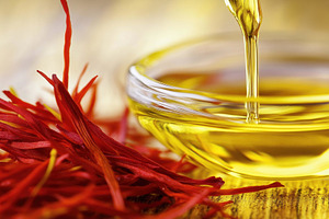 Saffron strands next to golden oil i, a Photo by Tanuart