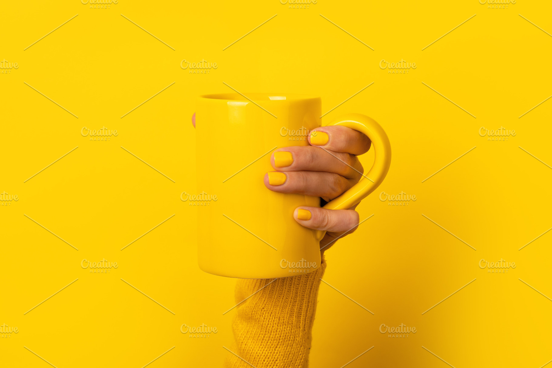 Close-up of a female hand with yellow nails holding a yellow mug, a Food & Drink Photo by Ales Munt
