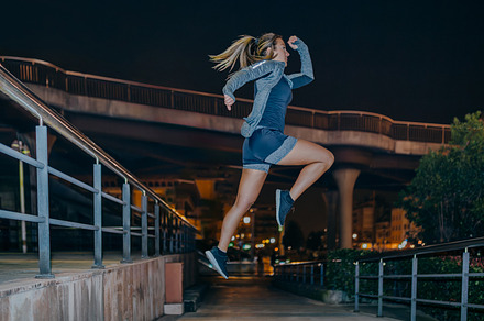 Woman jumping in cardio training exercise on the city at night, a Sports & Recreation Photo by davidpereiras