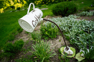 Decorative outdoor installation of a coffee mug in a lush green garden, a Photo by AS photostudio