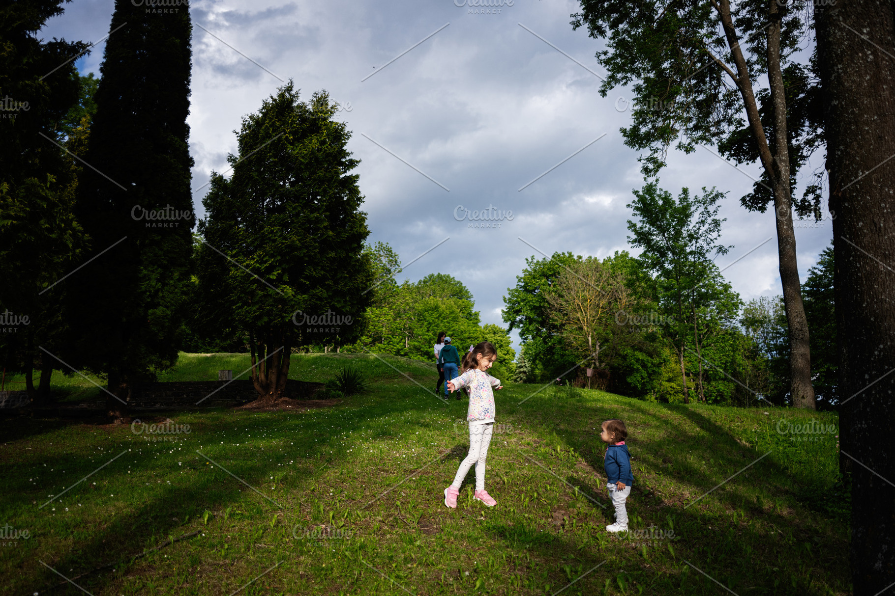 Children playing outdoors in a green park surrounded by tall trees, a Person Photo by AS photostudio