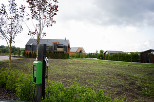 Electric vehicle charging at a rural home with modern design architecture, a Photo by AS photostudio
