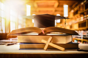 Stack of books with Bible and mortarboard in a classroom, a School & Education Photo by Davizro's Market