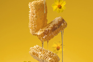 Fresh honey flows from a wooden spoon onto a levitating honeycom, a Food & Drink Photo by ndanko