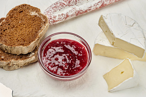 Sliced round head of Camembert cheese on a white board and, a Food & Drink Photo by ndanko