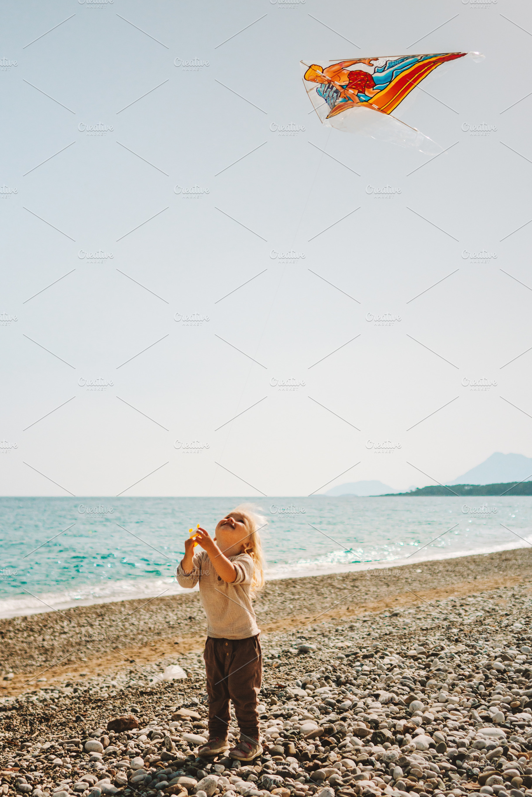 Child playing with kite flying outdoor walking on beach summer vacations travel, a Person Photo by e v e r s t