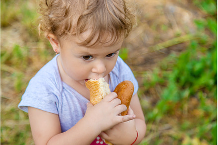 A child eats bread in the park, a Person Photo by yanadjana