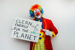 Clown holding sign about clean energy, a Person Photo by karrastock