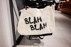 Canvas tote bag with Blah Blah lettering text displayed in a retail store rack, a Photo by AS photostudio